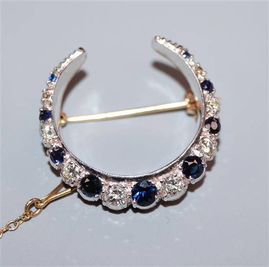 A 9ct yellow and white gold crescent brooch set with sapphires and diamonds, makers FRS Ltd, 27mm.